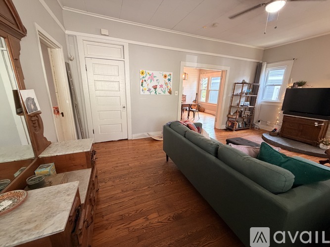 A living room with a green couch and wooden floors.