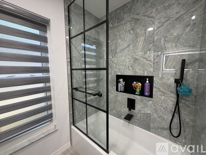 A bathroom with a glass shower door and a marble wall.