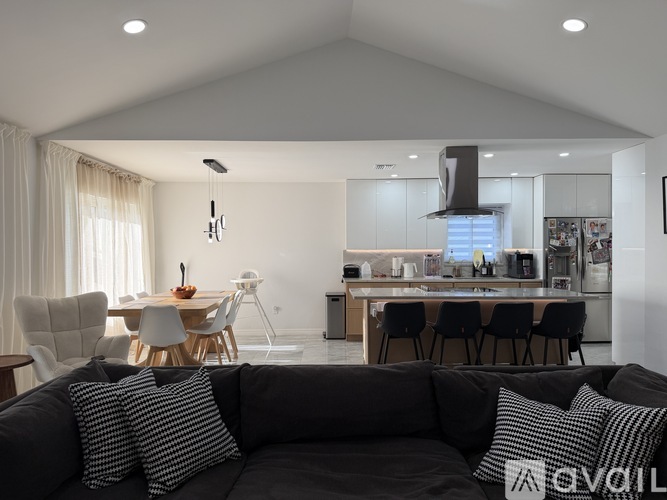 A modern living room with a grey sofa and a kitchen in the background.