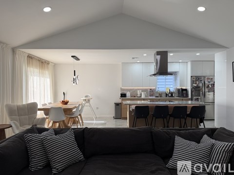A modern living room with a grey sofa and a kitchen in the background.