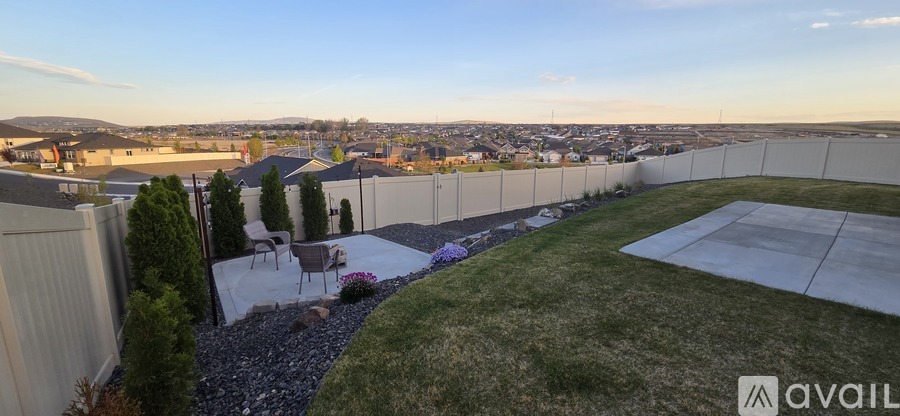 A backyard with a white fence and a patio table.