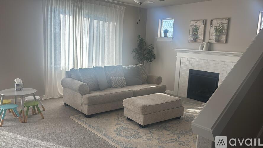 A living room with a grey couch, a white fireplace, and a rug.