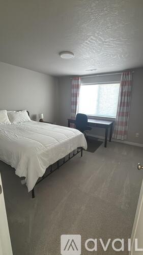 A bedroom with a bed, desk, and window.