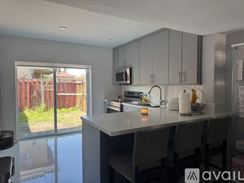 A modern kitchen with a large island and a view of a backyard.