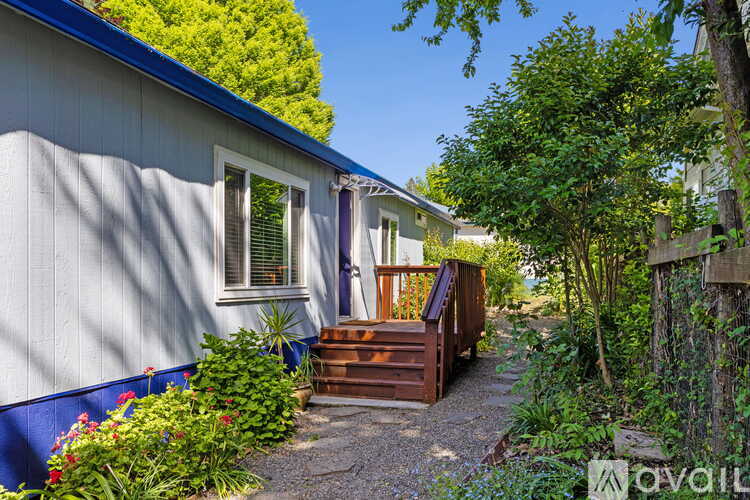 A house with a blue roof and white walls with a wooden deck.