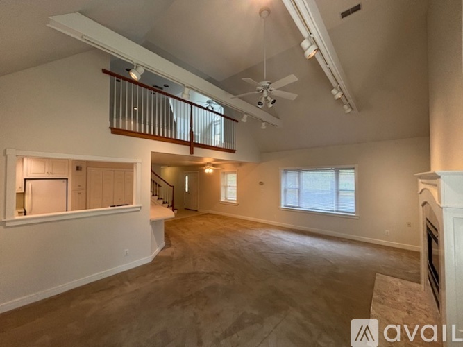 A spacious living room with a ceiling fan and large windows.