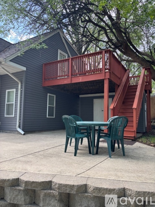 A patio with a table and chairs is in front of a house.