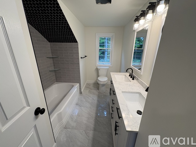 A bathroom with a white door, a window, a sink, and a bathtub.
