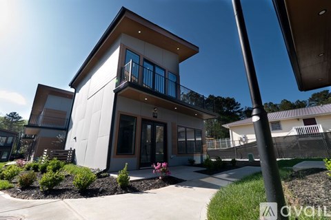 A modern house with a balcony and a garden in front.