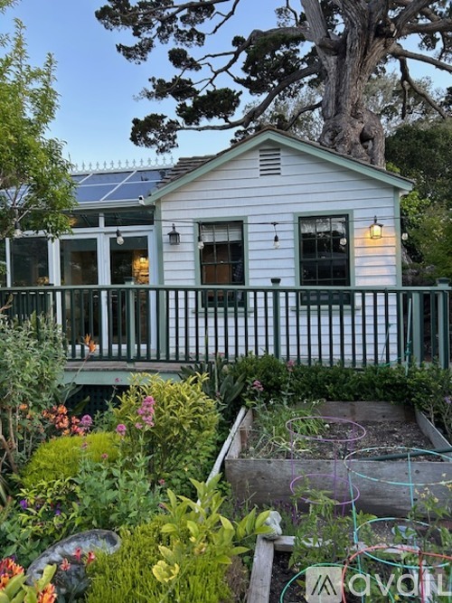 A white house with a green fence and a garden in front.