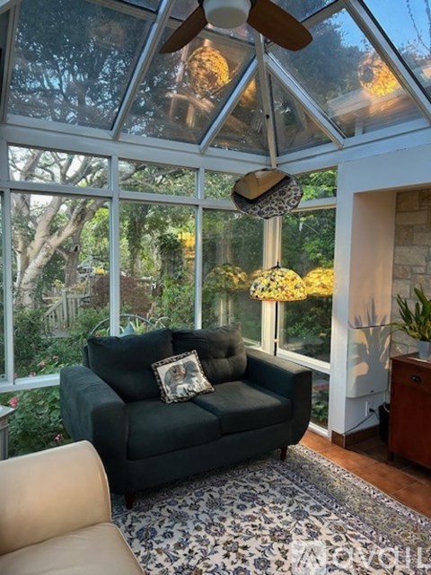 A living room with a green couch and a ceiling fan.