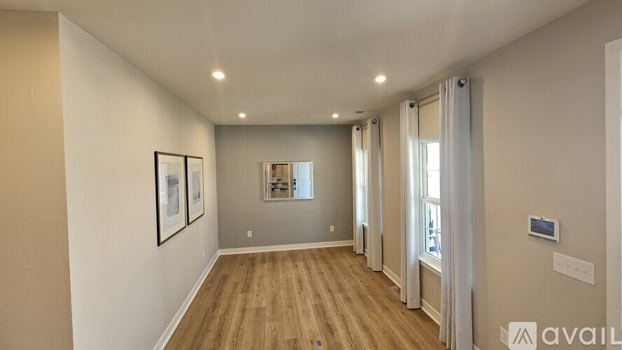 A spacious hallway with wooden floors and white walls.