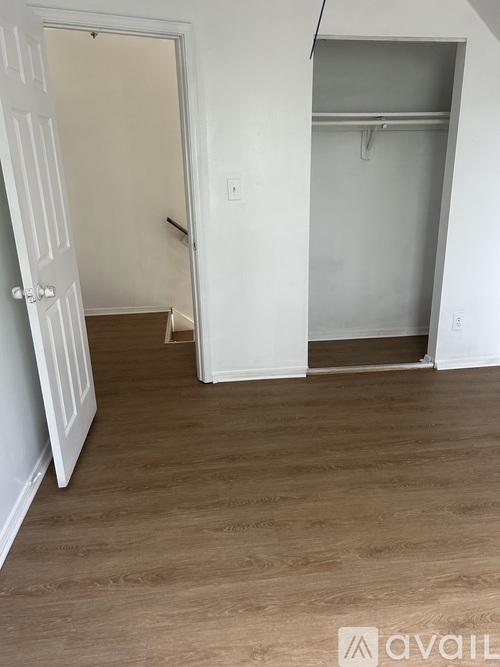 A room with a white door and a white wall with a shelf.