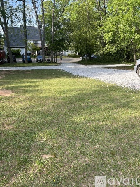 A grassy area with a gravel path and trees in the background.
