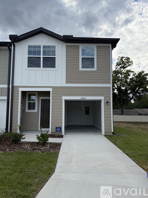 A two-story house with a garage and a driveway in front.