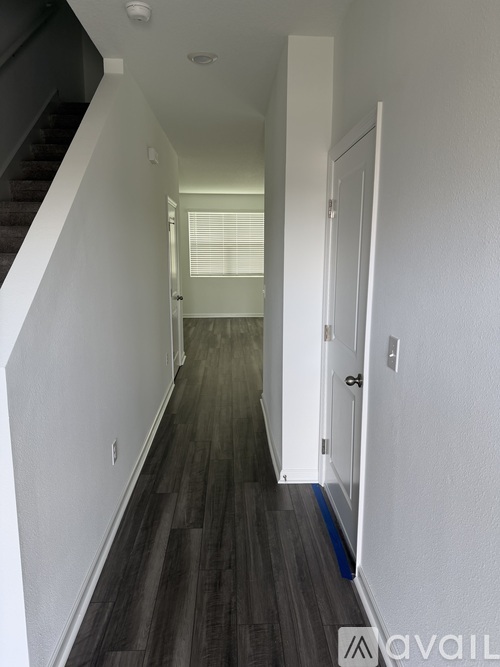 A long hallway with a staircase on the left and a door on the right.