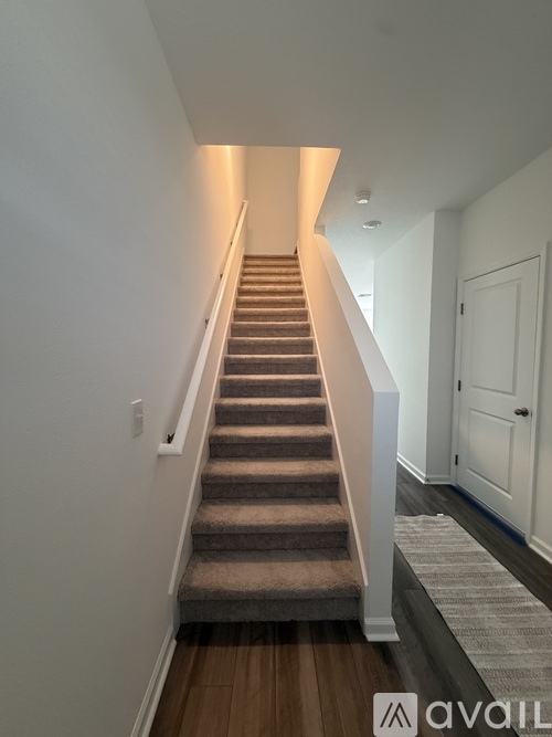 A staircase with a carpeted runner and white walls.