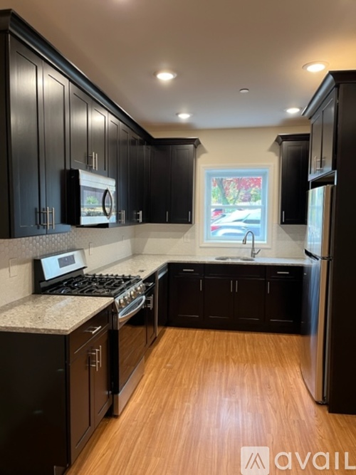 A kitchen with black cabinets and a wooden floor.