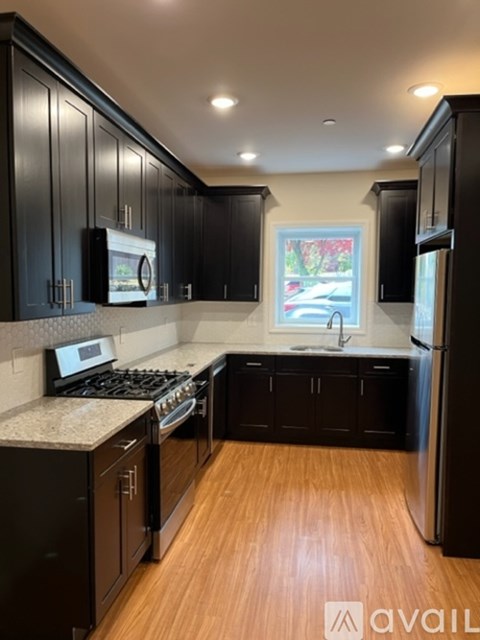A kitchen with black cabinets and a wooden floor.