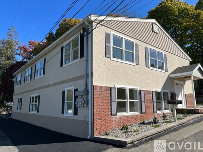 A two-story house with a beige and red brick exterior is for sale.