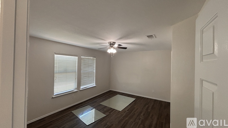 A room with a ceiling fan and a window with blinds.