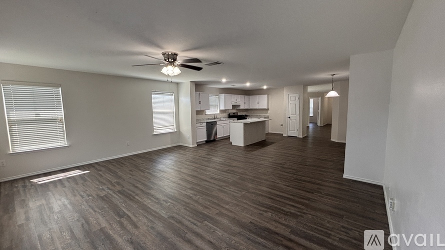 A spacious room with wooden flooring and a ceiling fan.
