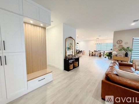 A modern living room with a brown leather couch and white cabinets.