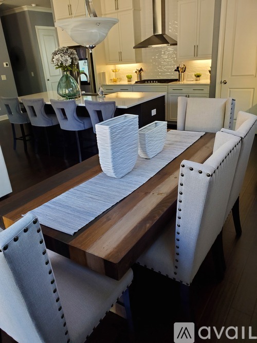 A modern dining room with a wooden table and white chairs.