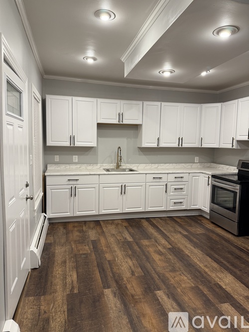 A kitchen with white cabinets and wooden floors.