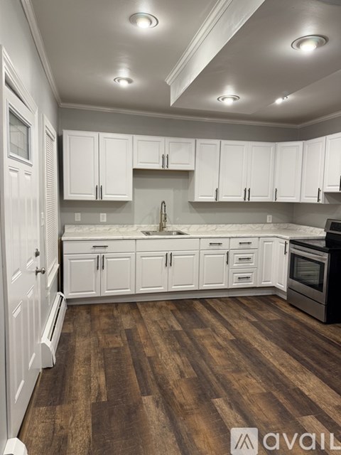 A kitchen with white cabinets and wooden floors.