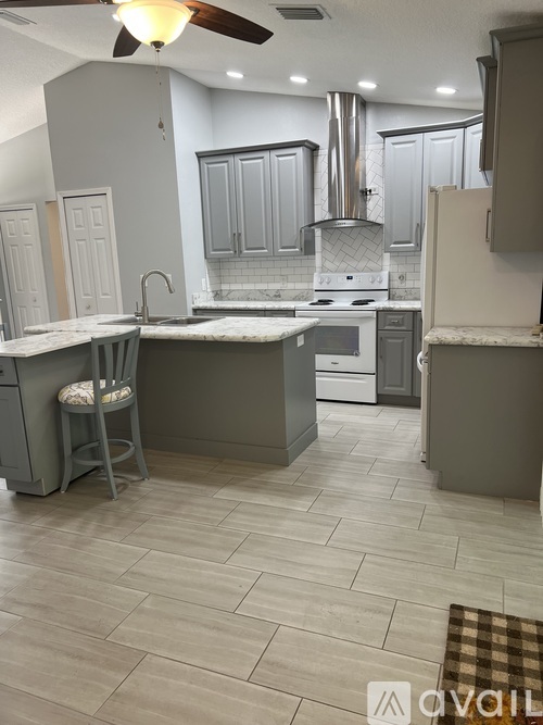 A kitchen with a white stove top oven and a fan on the ceiling.