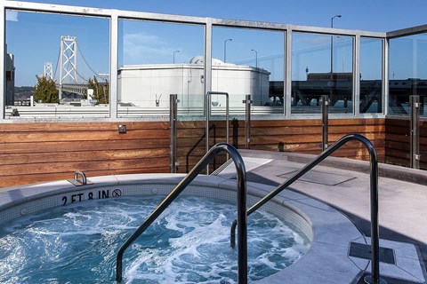 A hot tub on a balcony with a view of a bridge and a building in the background.