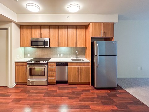 A kitchen with wooden cabinets and a stainless steel refrigerator.
