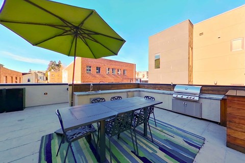 A patio with a table and chairs under a yellow umbrella.