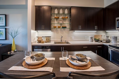 A modern kitchen with a dining table set for two.
