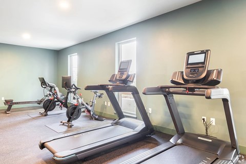 A room with a treadmill, elliptical trainer and a stationary bike.