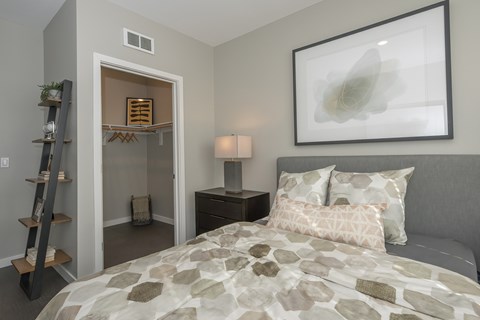 A bedroom with a bed, nightstand, and a painting on the wall.