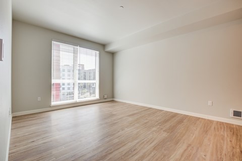 A room with wooden flooring and a window with blinds.