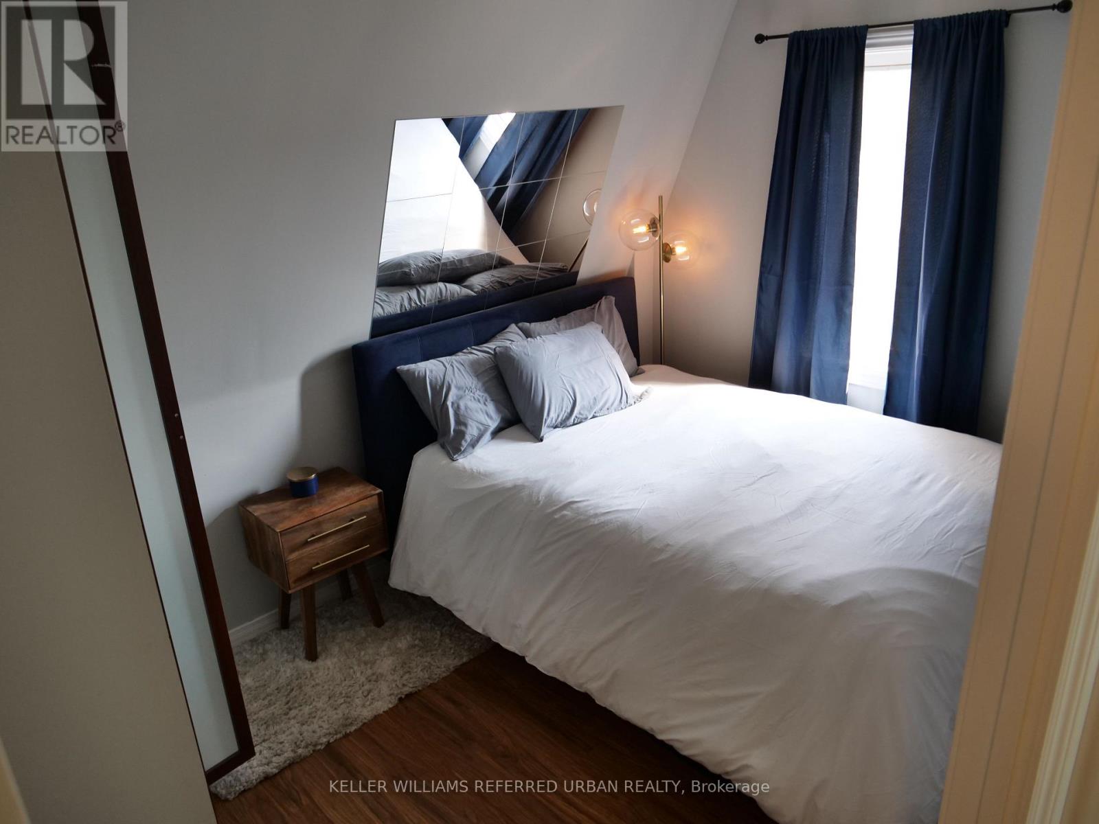 A bedroom with a bed, nightstand, and window.