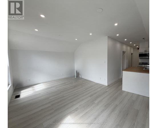 A spacious room with wooden flooring and white walls.