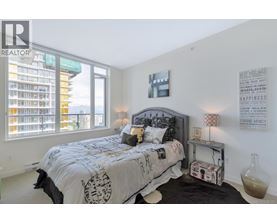 A bedroom with a large bed and a window overlooking a city.