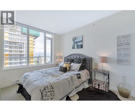 A bedroom with a large bed and a window overlooking a city.