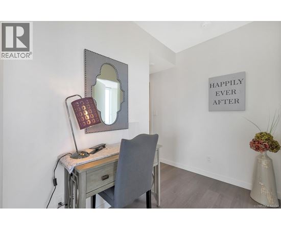 A desk with a chair and a mirror with a light on it.