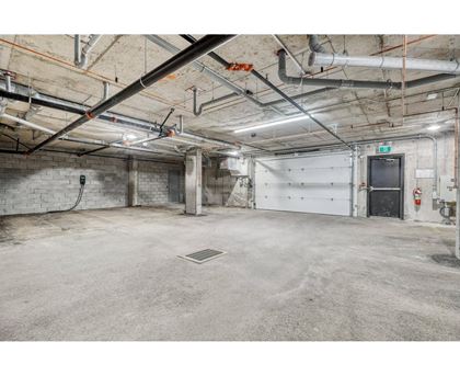 A large, empty industrial-style room with a concrete floor and exposed pipes on the ceiling.