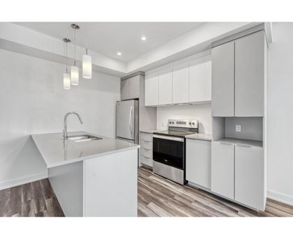 A modern kitchen with white cabinets and stainless steel appliances.
