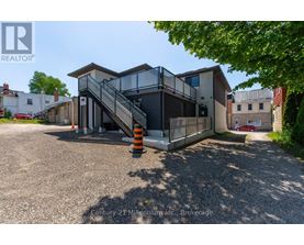 A modern house with a glass staircase and a gravel driveway.