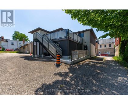 A modern house with a glass staircase and a gravel driveway.