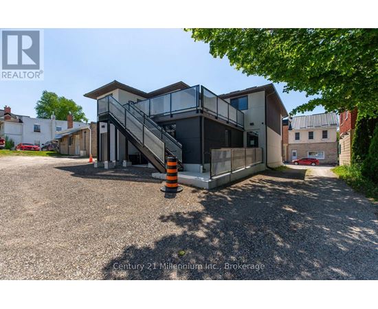 A modern house with a glass staircase and a gravel driveway.