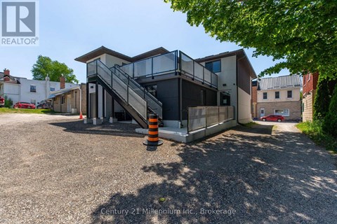 A modern house with a glass staircase and a gravel driveway.
