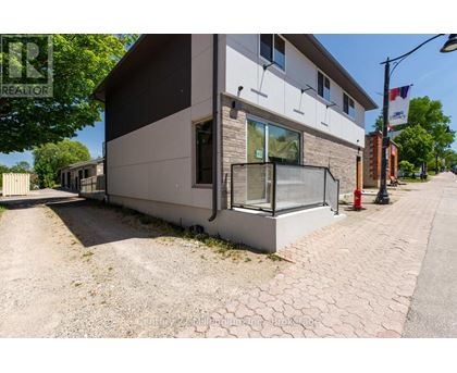 A modern house with a grey and white exterior and a brick pathway leading to the front door.